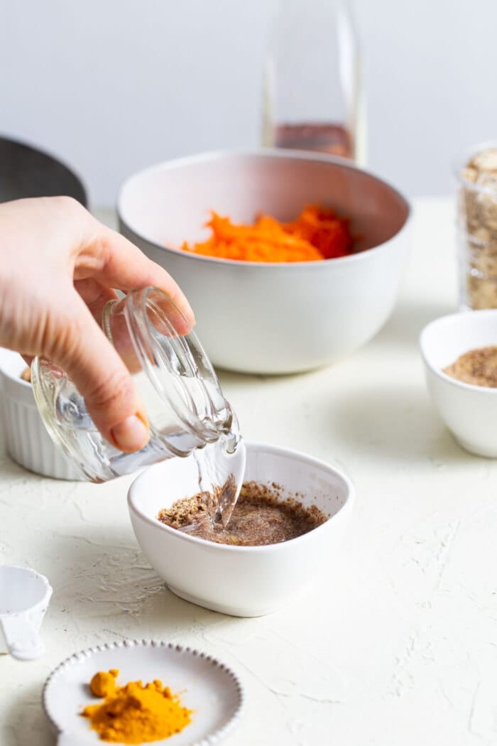 Pouring water in a small dish with ground flax in it.