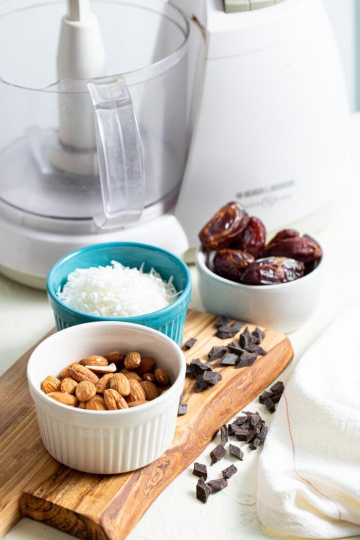 Almonds, coconut, dates and chocolate chips in containers on a countertop.