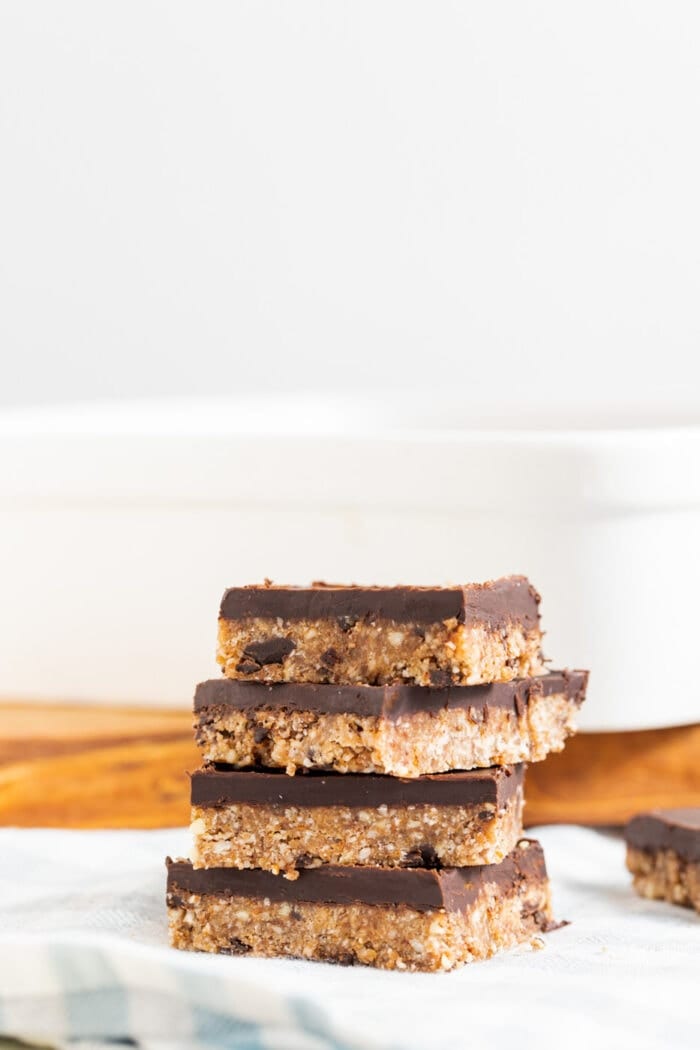 A stack of 4 almond coconut bars topped with chocolate.
