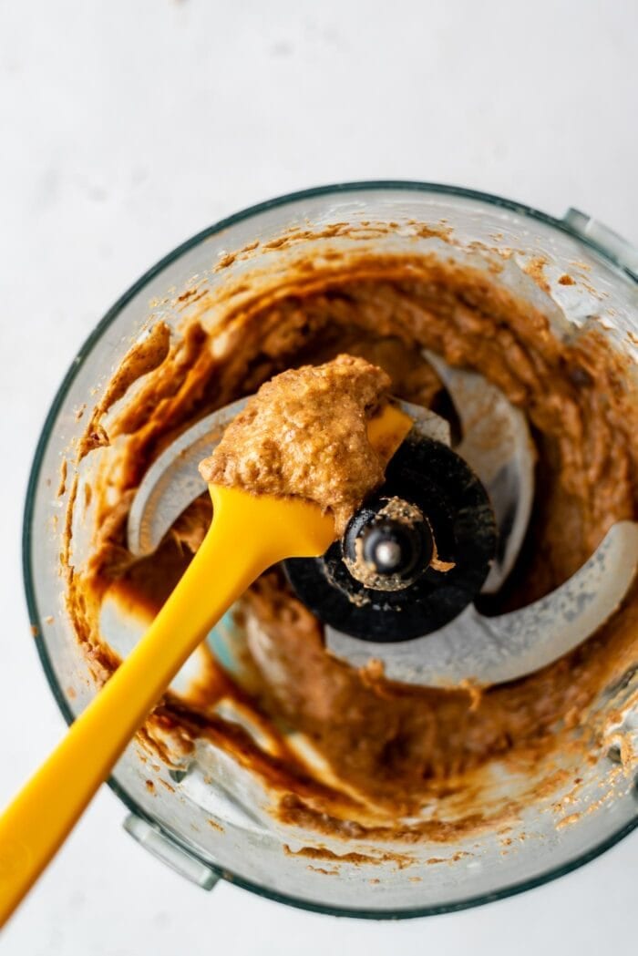 Blended, creamy caramel in a food processor with a spatula.
