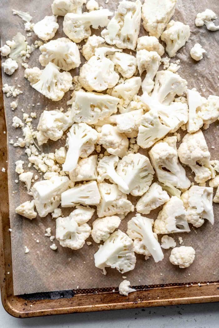 Chopped cauliflower on a lined baking tray.