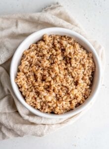 Cooked farro in a bowl sitting on top of a dish cloth.