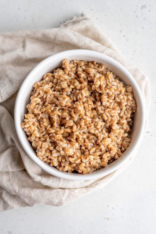 Cooked farro in a bowl sitting on top of a dish cloth.