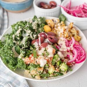 Bowl with roasted cauliflower, olives, pickled red onion, kale and tahini.