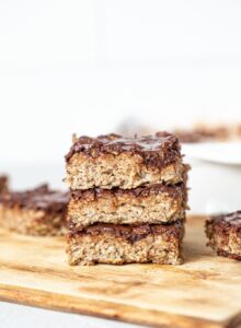 A stack of baked oatmeal bars topped with chocolate..