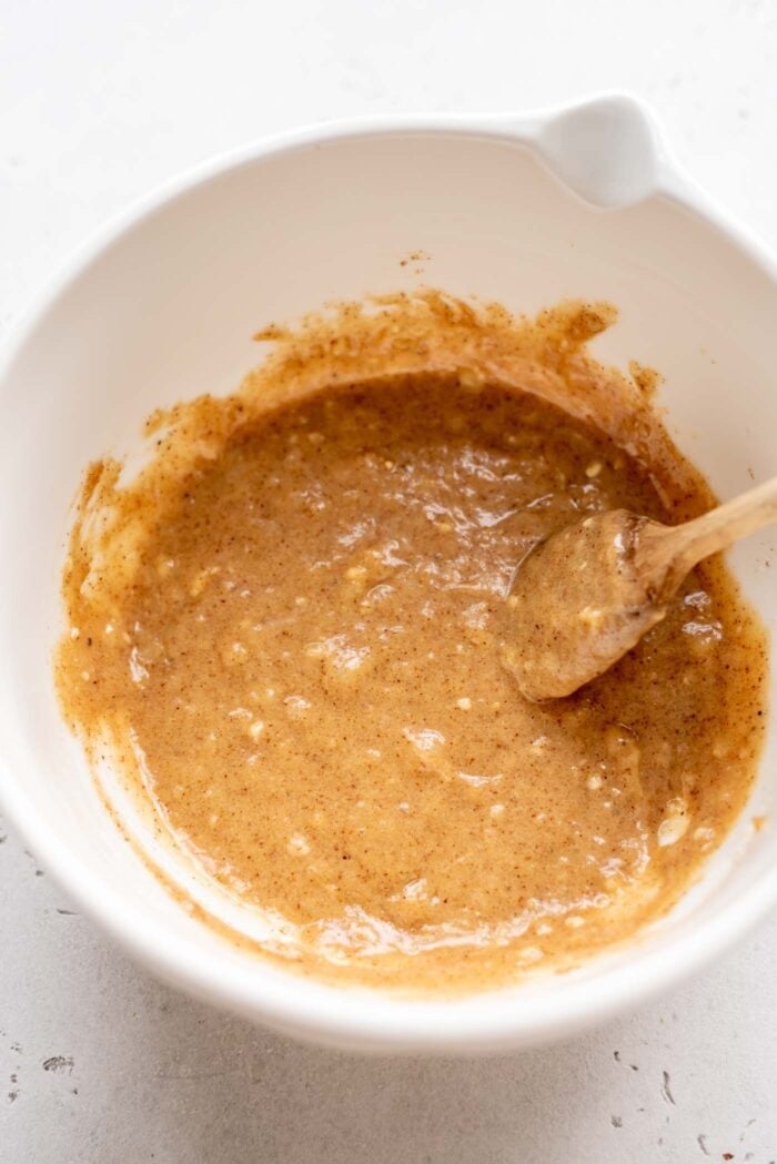 Mashed banana mixed with almond butter in a mixing bowl with a spoon.