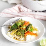 Vegetable green curry on top of rice in a bowl.