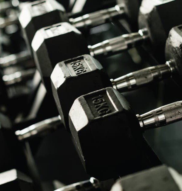 Multiple black rubber dumbbells on a rack.