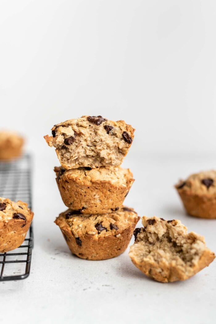 A stack of 3 chocolate chip muffins with a bite taken out of the one on top.