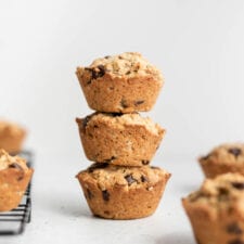 A stack of 3 small muffins on a counter beside a cooling rack.