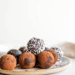 A plate of raw brownie balls rolled in cocoa powder and shredded coconut.