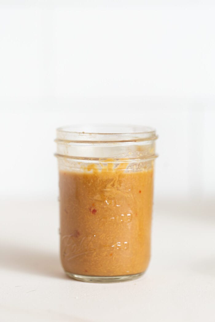 A small jar of peanut sauce sitting on a counter.
