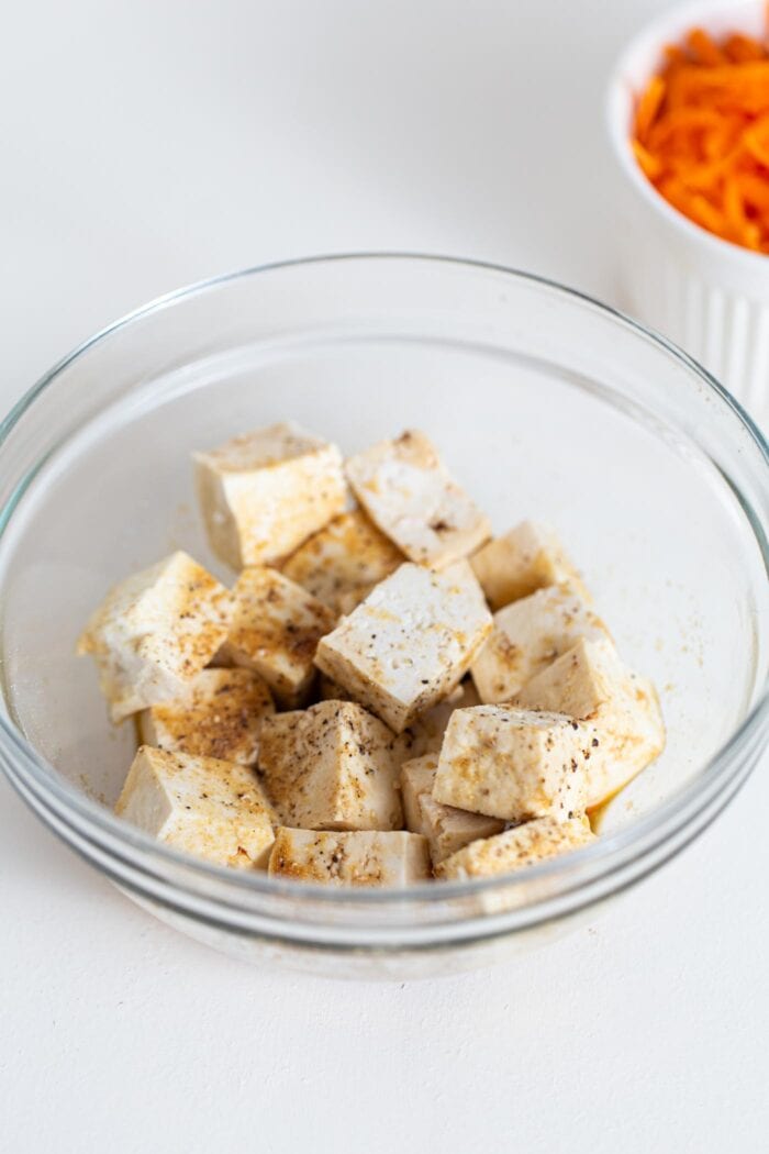 Cubed tofu in a bowl with soy sauce and pepper.