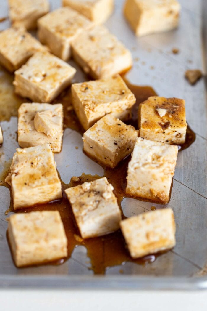 Tofu cubes coated in soy sauce on a baking tray.