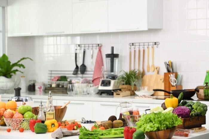 A kitchen with fruits and vegetables on the counter.