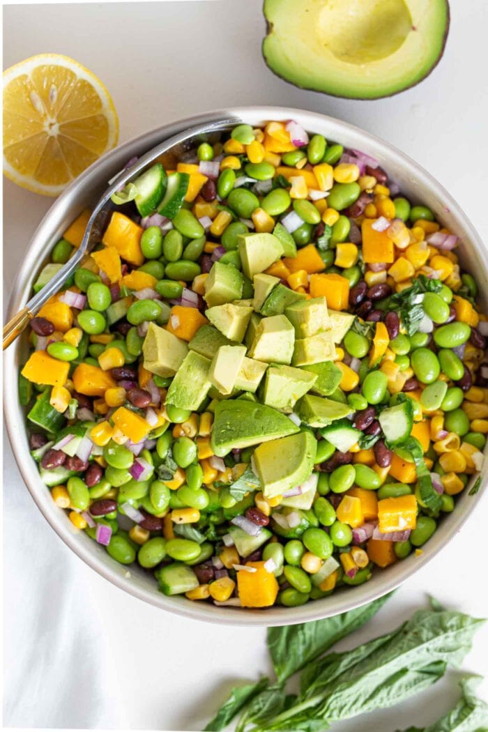 An overhead shot of a large bowl of salad with edamame, mango, cucumber and avocado.