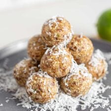 A stack of energy balls covered in shredded coconut on a plate.