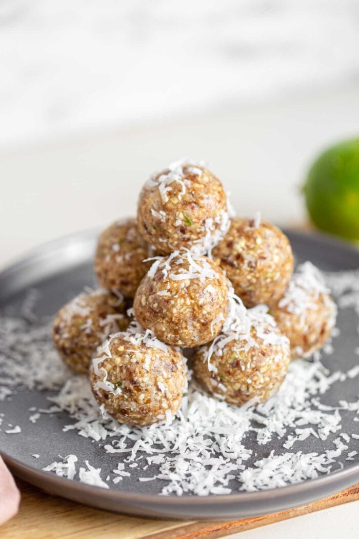 A stack of energy balls covered in shredded coconut on a plate.