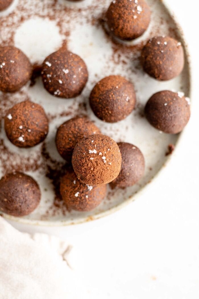 An overhead image of raw chocolate energy balls coated in cocoa powder on a plate.