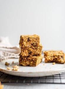 A stack of 3 baked pumpkin oatmeal bars on a plate.