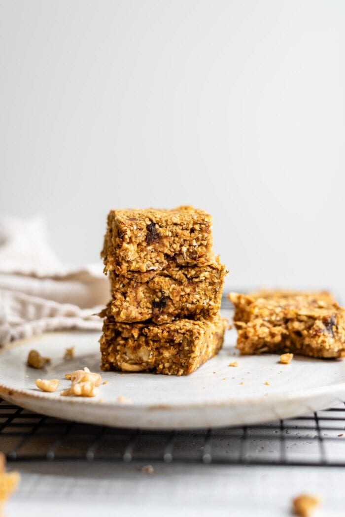 A stack of 3 baked pumpkin oatmeal bars on a plate.
