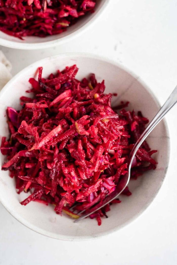 Overhead shot of a beet, apple and cabbage slaw in a bowl with a fork.