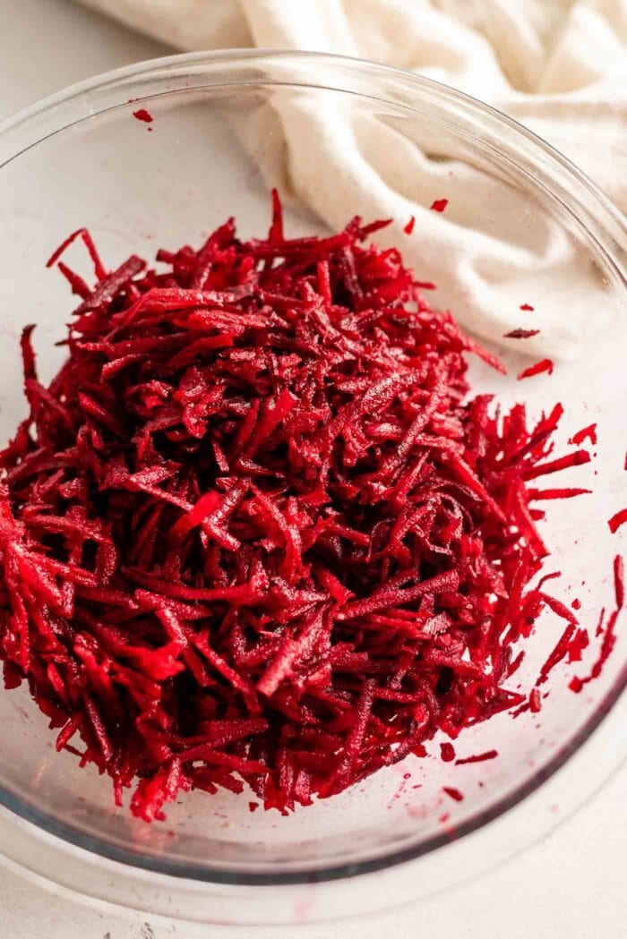 Raw grated beet in a glass mixing bowl.