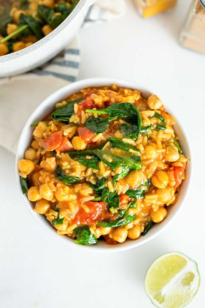 A bowl of chickpea stew with rice, spinach and tomato.
