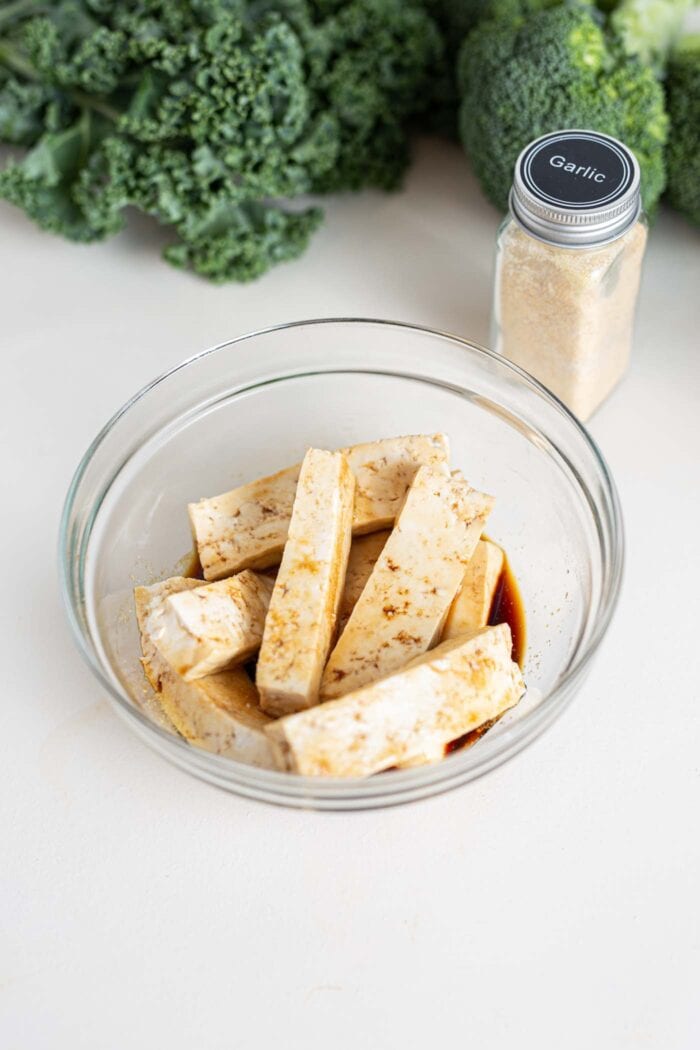 Slices of tofu in a small bowl with soy sauce.