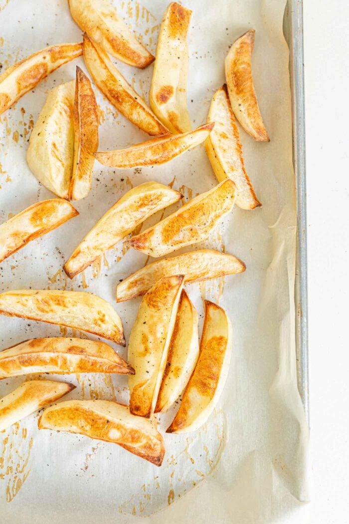 Baked fries on a baking tray lined with parchment paper. 