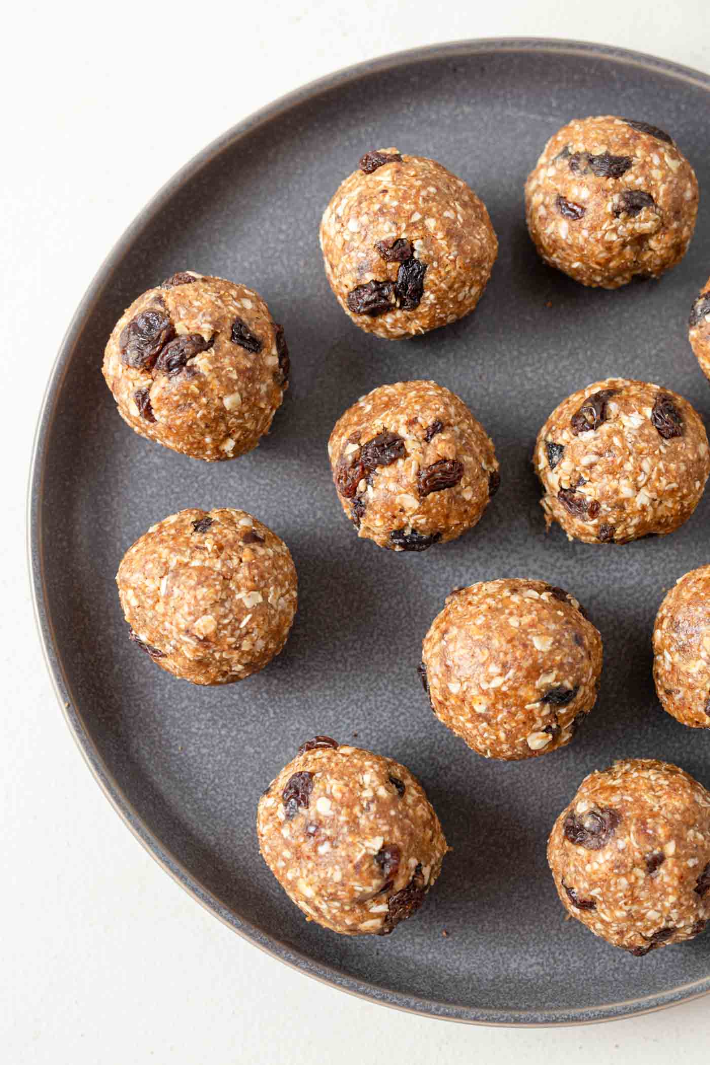 A number of no-bake cookie dough balls with raisins on a plate.