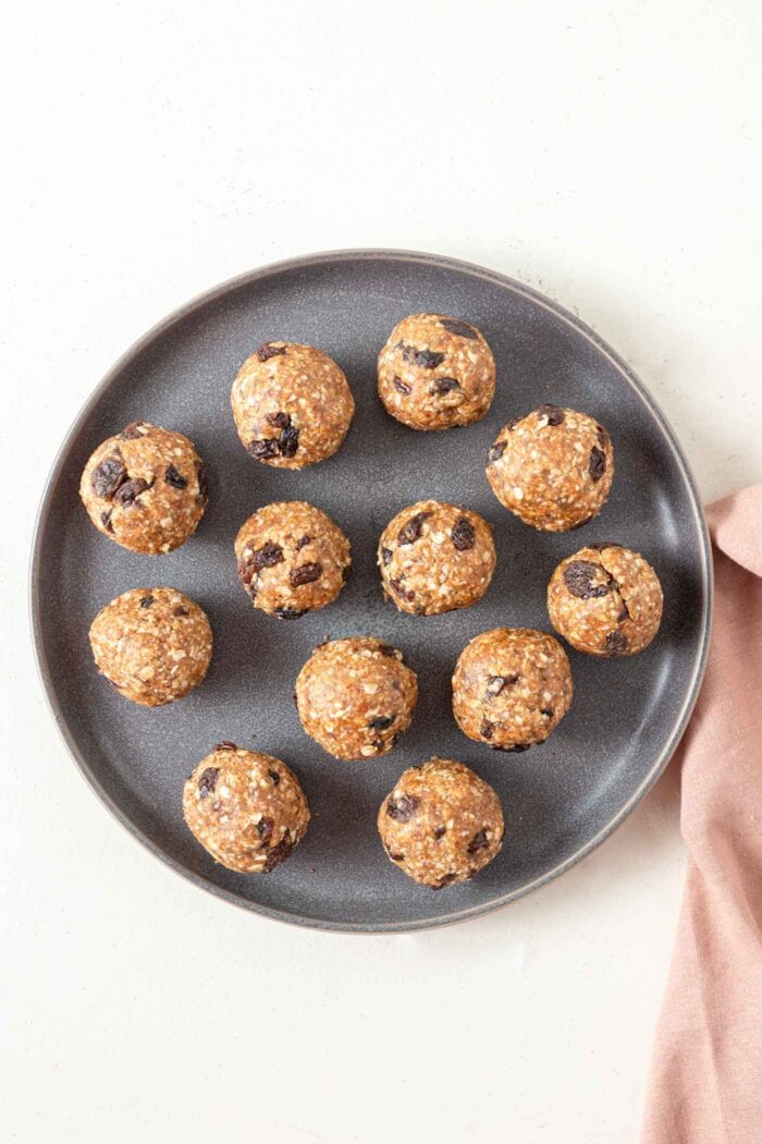 A number of no-bake cookie dough balls with raisins on a plate.