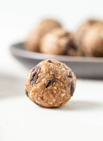 A close up of a cookie dough ball with raisins in it on a counter top.