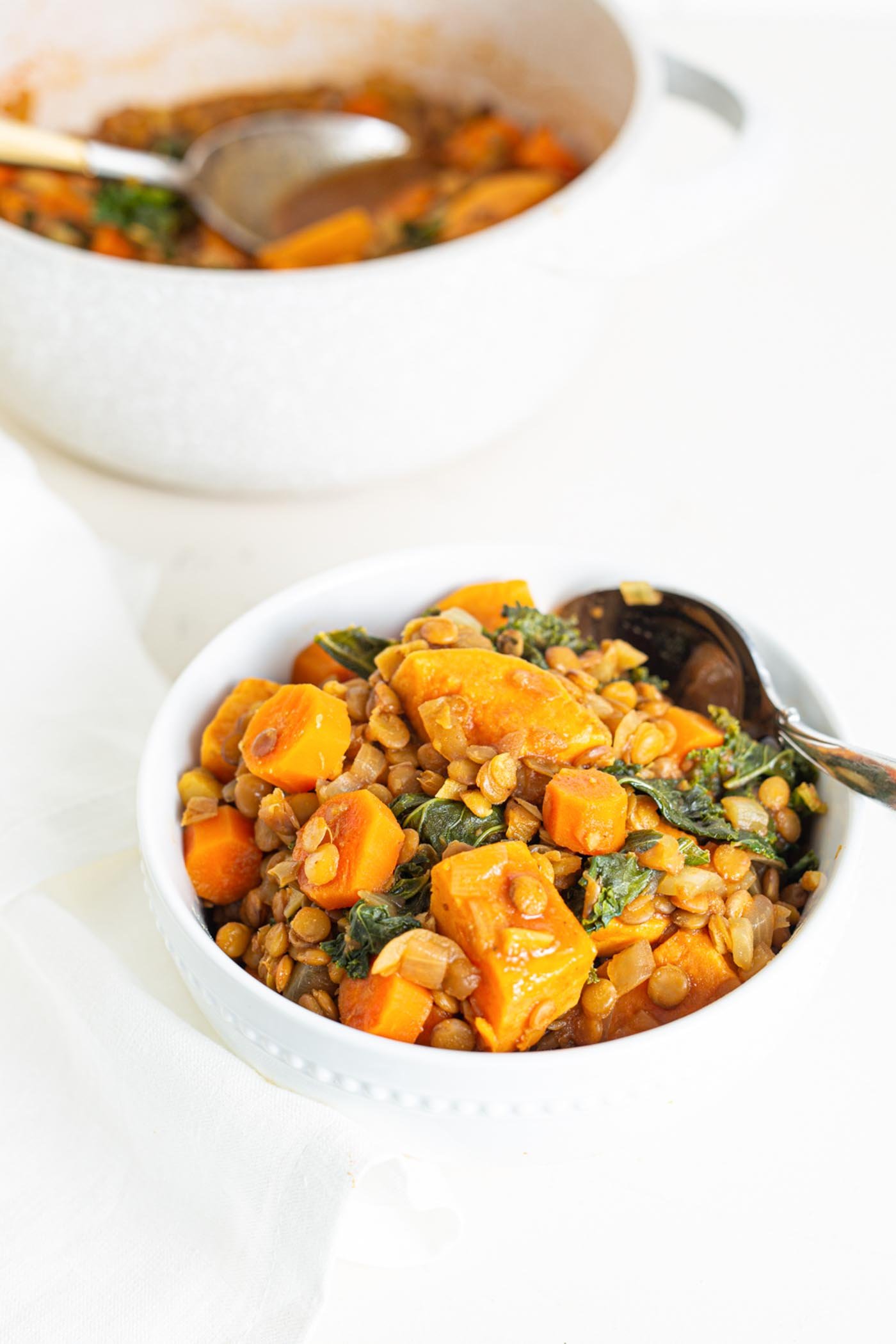 A bowl of sweet potato lentil stew with kale mixed into it.