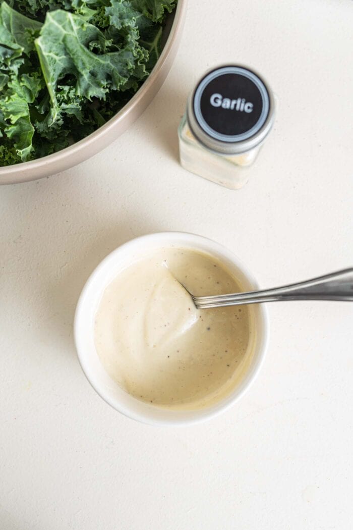Caesar salad dressing in a bowl with a spoon.