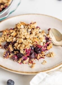 Blueberry crisp on a plate with a spoon.