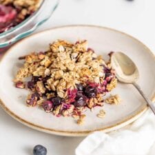 Blueberry crisp on a plate with a spoon.