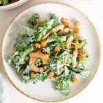 Overhead image of a kale caesar salad with chickpeas and coconut bacon on a plate.