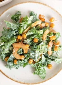 Overhead image of a kale caesar salad with chickpeas and coconut bacon on a plate.