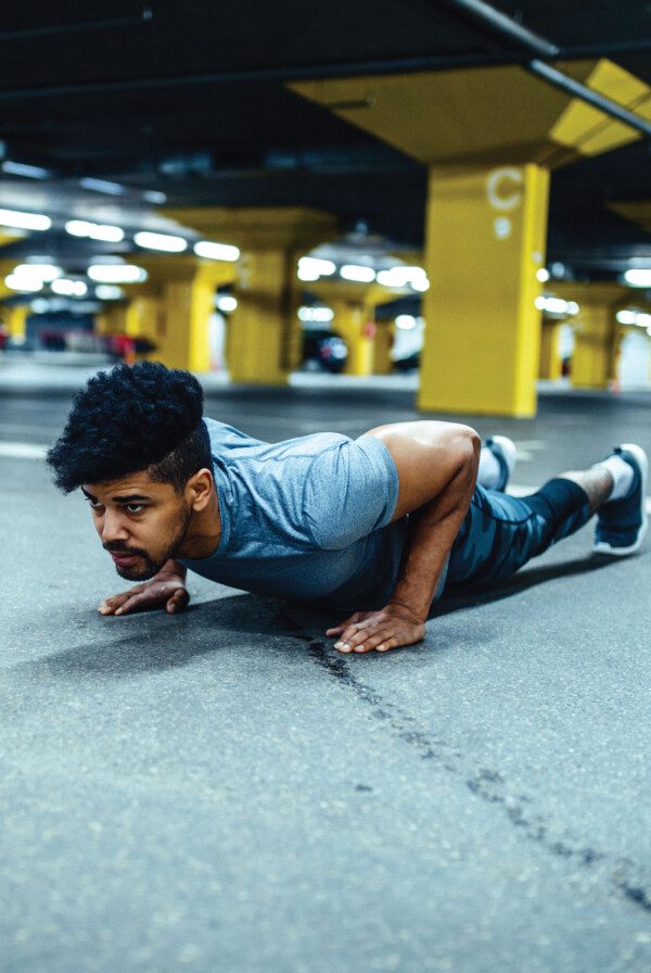 Fit man performing a push-up in a parking garage.