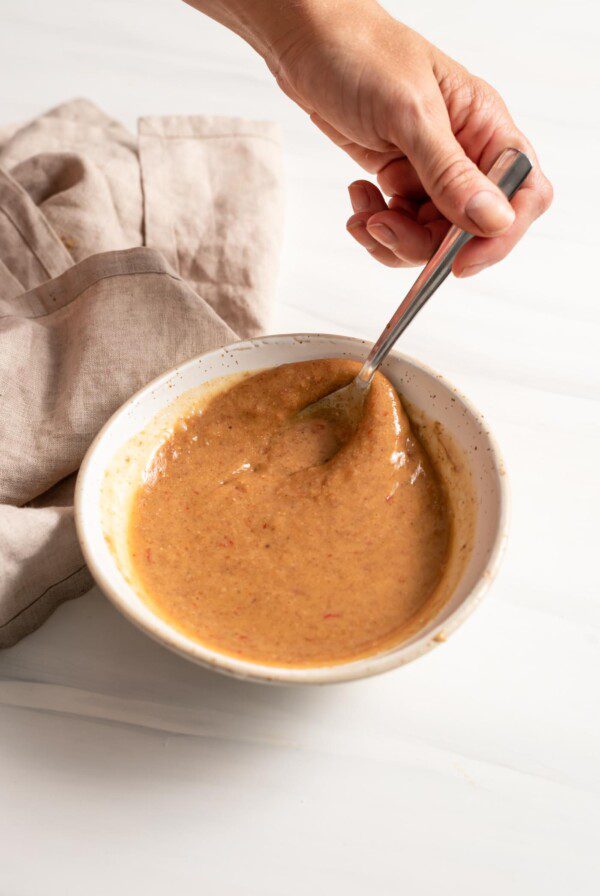 Mixing a creamy sauce in a small bowl with a spoon.