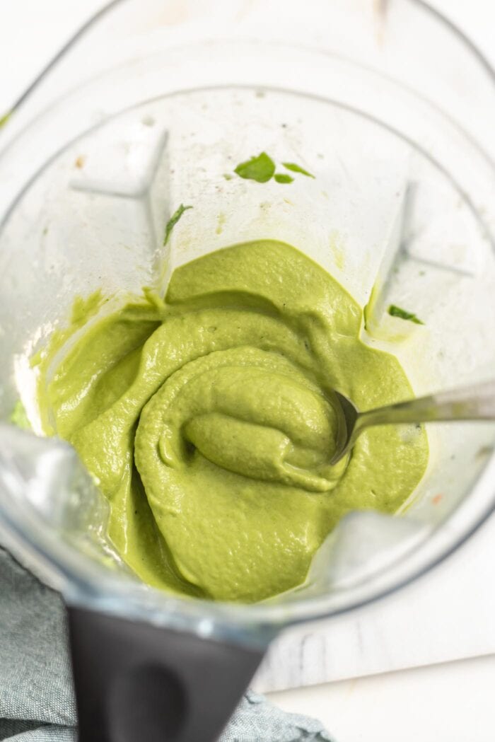 A thick, green smoothie in a Vitamix container.