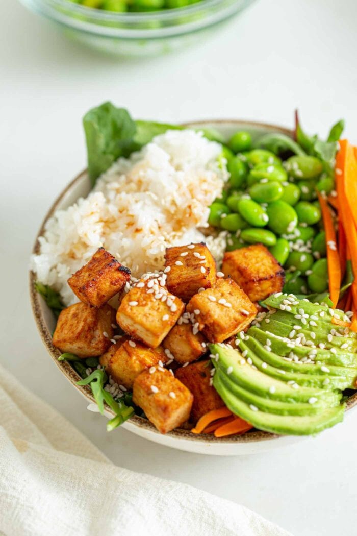 Crisp baked tofu in a bowl with avocado, rice and edamame.