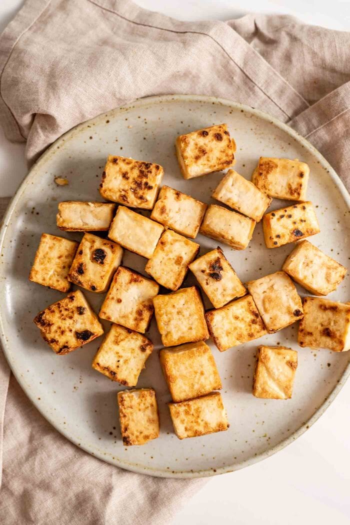 Cooked, crispy tofu cubes on a plate.