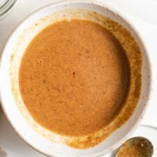 A bowl of creamy almond butter sauce with a spoon beside it.