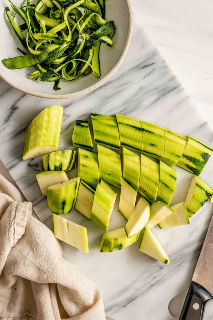 Peeled and chopped zucchini on a marble cutting board.