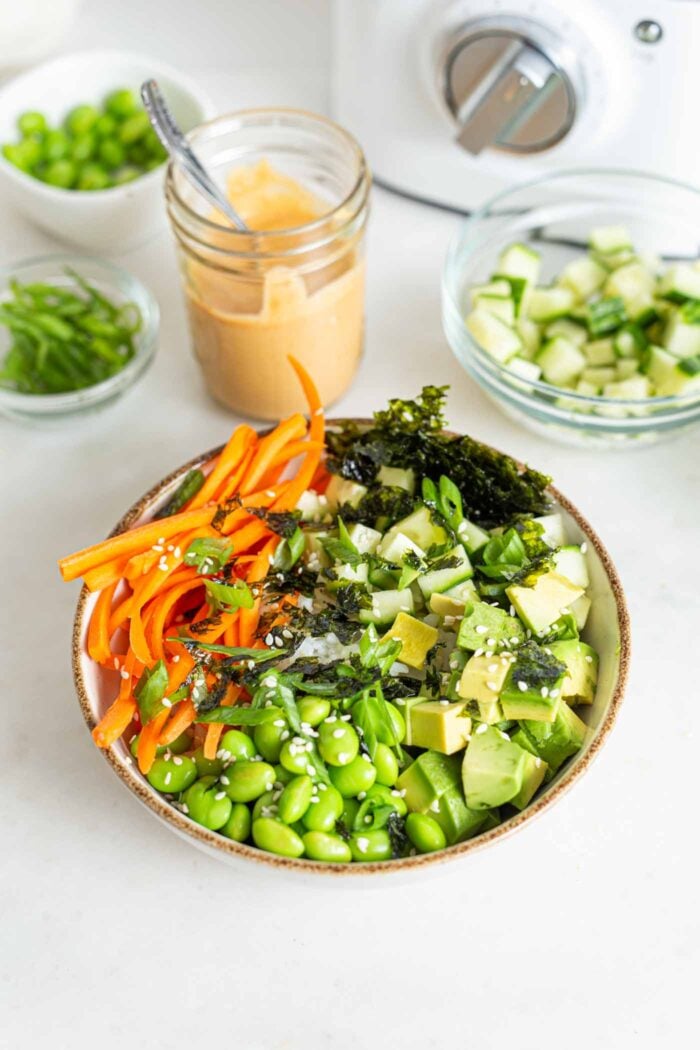 Rice, cucumber, seaweed, avocado, edamame and carrot in a bowl.