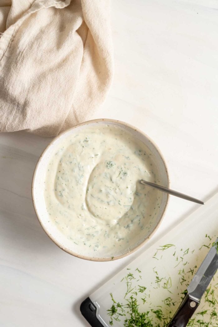 A creamy sauce with dill in a bowl with a spoon.