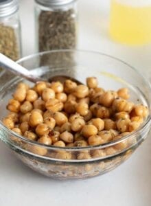 A bowl of marinated chickpeas with a spoon in it.