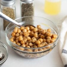 A bowl of marinated chickpeas with a spoon in it.